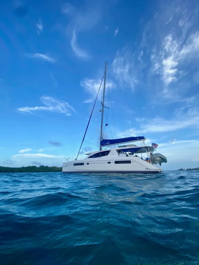 A white catamaran from Belize Sailing Vacations is floating in the ocean.