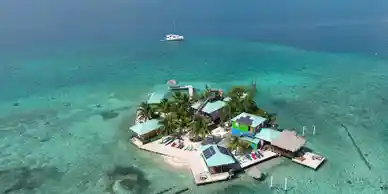 An aerial view of an island with a boat on it, showcasing the beauty of Belize.