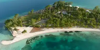 An aerial view of a small island in the ocean, located off the coast of Belize.