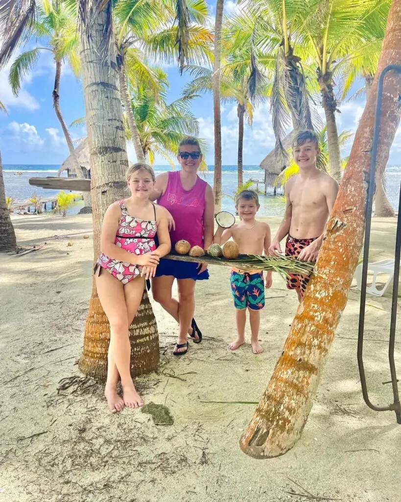 A family posing for a picture on a beach with palm trees during their Belize vacation.