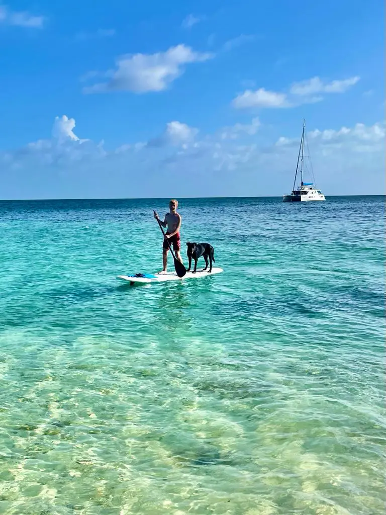 A man enjoying a paddle board adventure accompanied by his loyal canine companion during a relaxing vacation.
