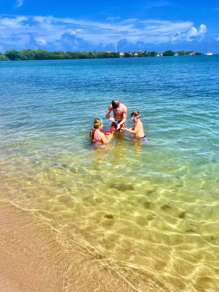 Three people enjoying a Belize beach vacation, playing in the water during a sailing tour.