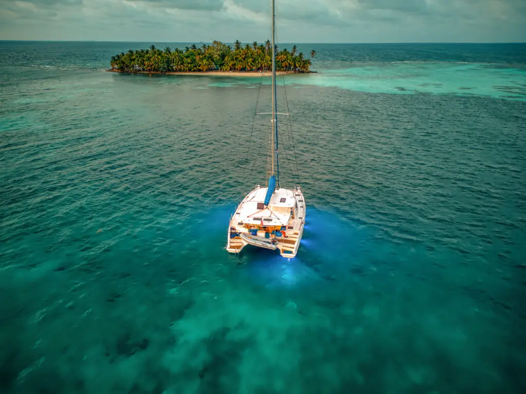 A catamaran, featured in the Luxury Yacht Gallery, sails in the ocean near an island.