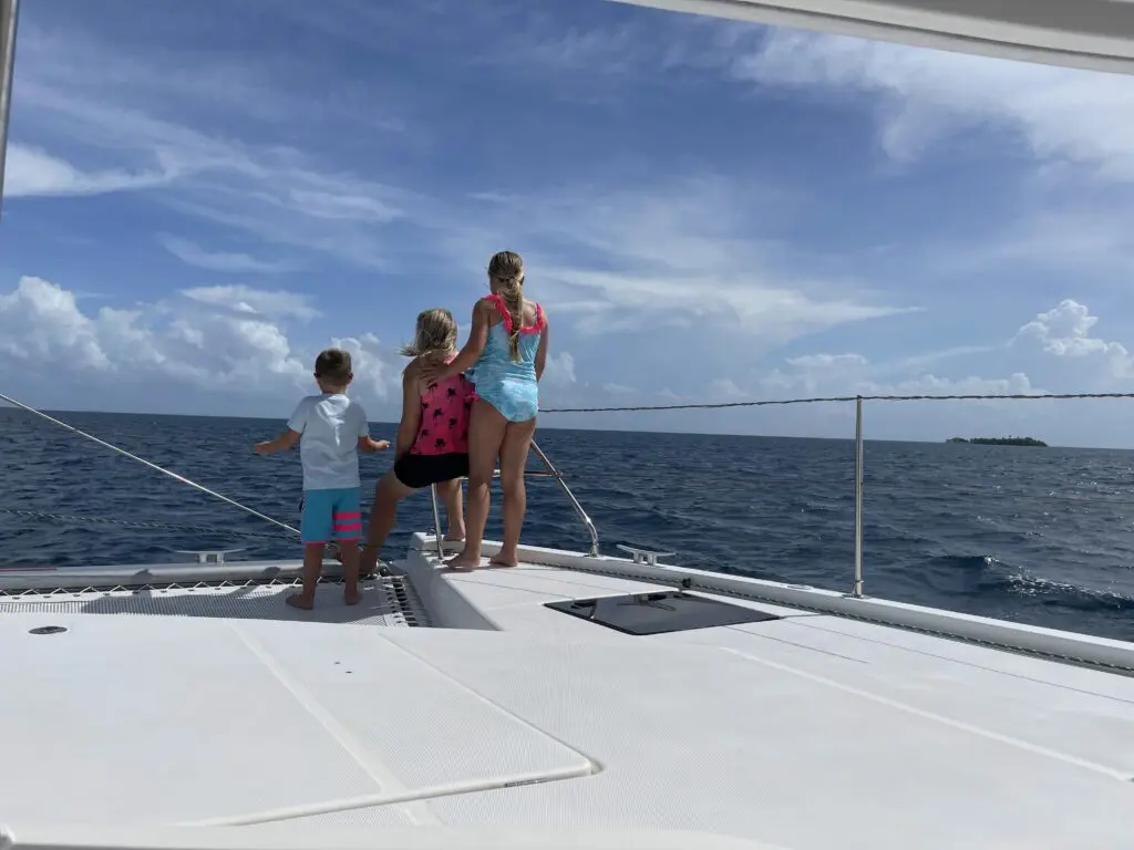 Two children standing on the deck of a catamaran during a Belize Sailing Vacation.