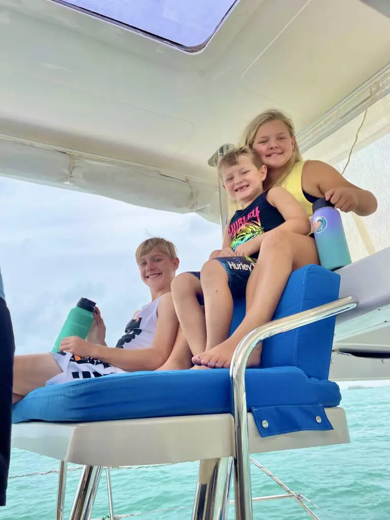 Three children enjoying a Belize sailing vacation on the back of a boat.