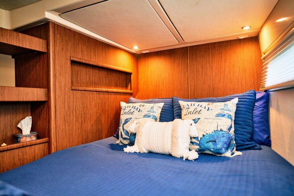 A bedroom on a boat with a blue comforter and pillows.