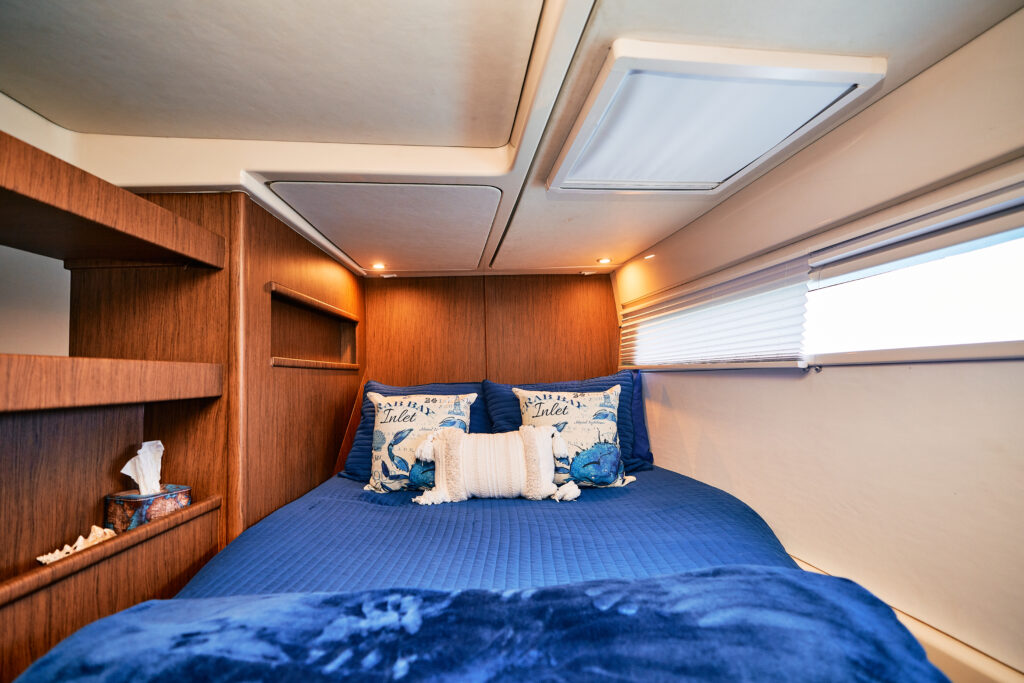 A bed in a boat with a blue comforter.
