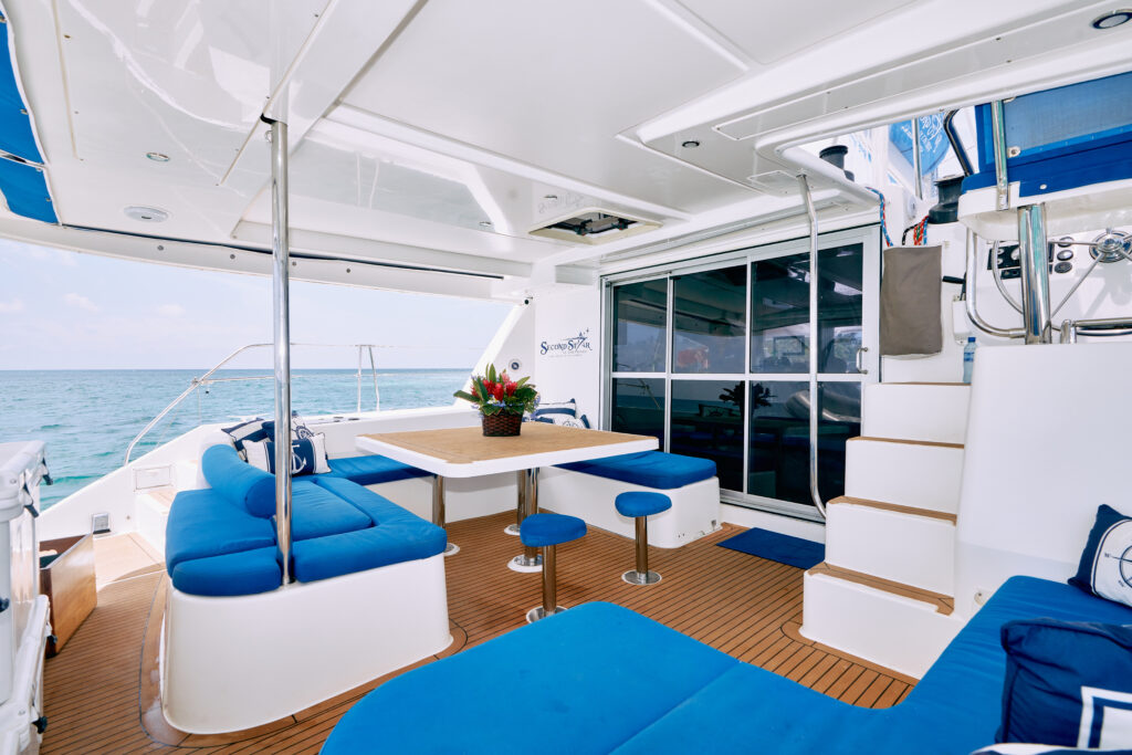 The interior of a catamaran with blue couches and a table.