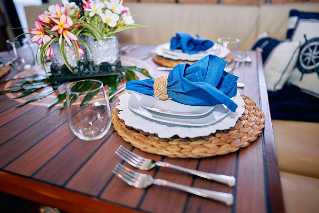 A luxury table setting with blue napkins and silverware in a yacht gallery.