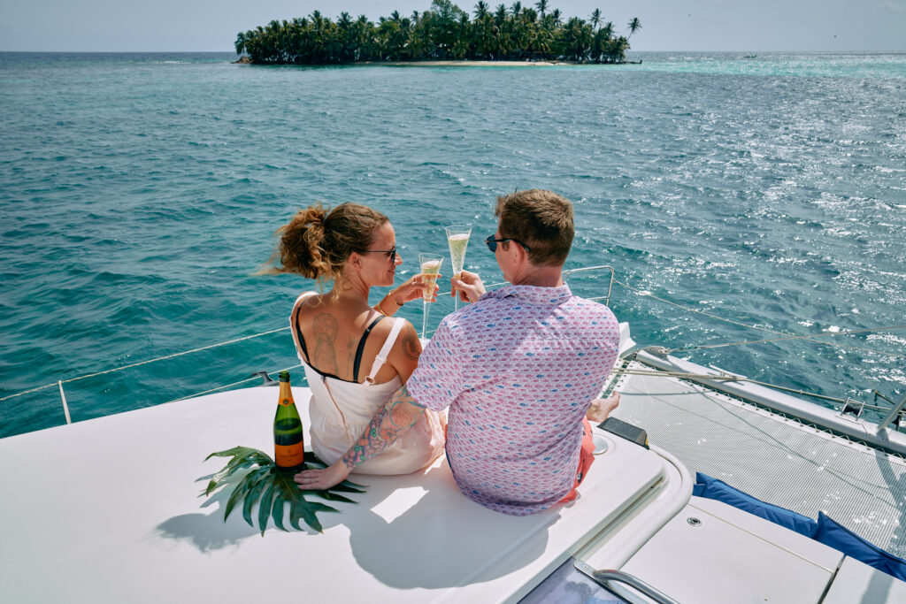 A couple enjoying champagne on a boat during their Belize Sailing Vacation.