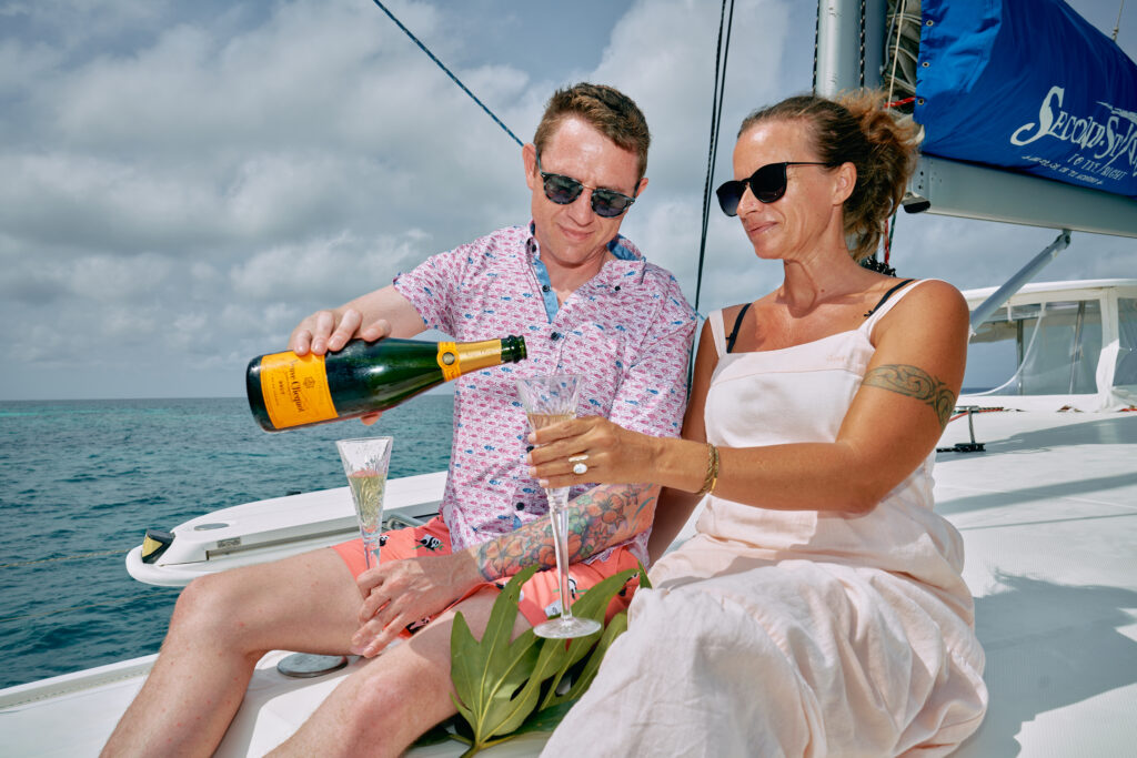 Two people enjoying a Belize Sailing Vacation on a boat, sipping champagne.